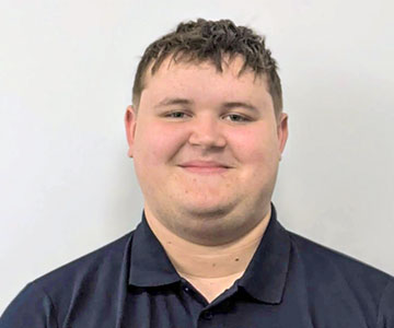 Portrait eines jungen Mannes, lächelnd vor neutralem weißen Hintergrund.