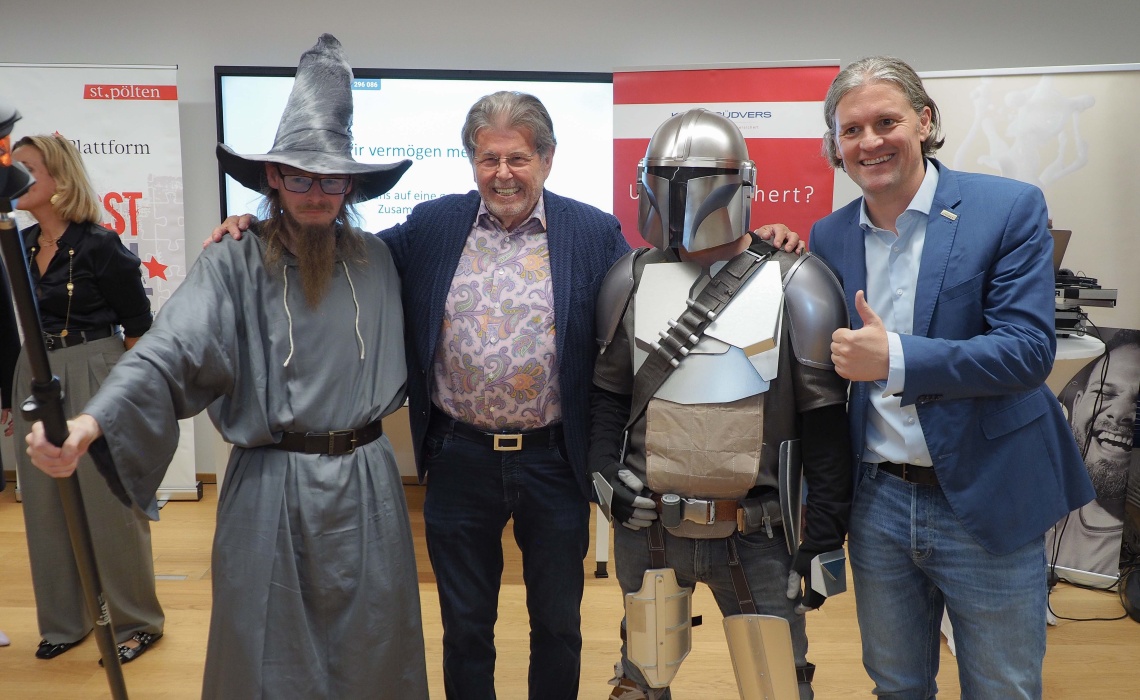 Gruppenfoto mit 4 Personen: 2 in Anzügen, die anderen beiden verkleidet als Zauberer und ScienceFiction Figur