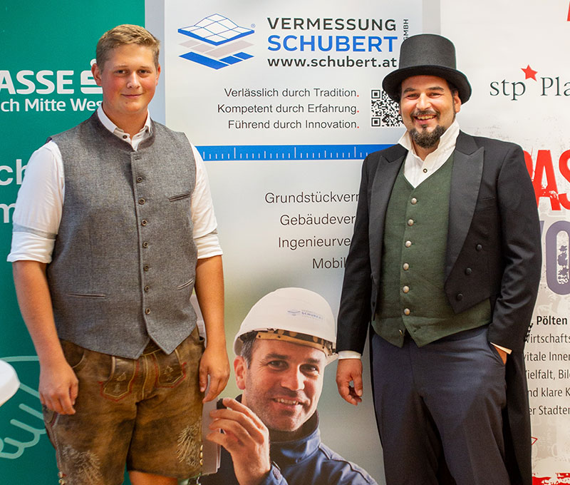 Foto v. 2 Männern, 1 in Tracht, der 2. in viktorianischem Kostüm mit Zylinder und Frack