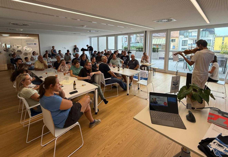 Ein Violinist spielt, begleitet mit Klavier in einem Vortragssaal vor ca. 40 Personen
