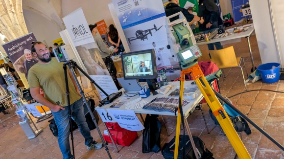 Ein Messestand mit verschiedenen Vermessungsgeräten, ein Mann links im Bild bedient eines davon.