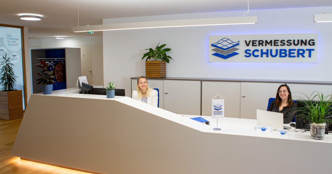 2 Frauen sitzen hinter der Rezeption eines modernen B&uuml;ros