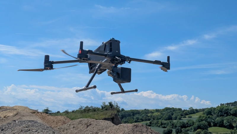 Eine schwarze Vermessungsdrohne Modell DJI Matrice 400 fliegt &uuml;ber eine Schottergrube